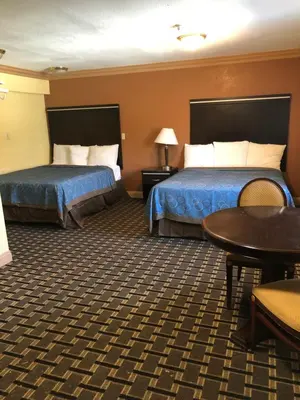 a hotel room with two beds and a table at Glendora Motel in Glendora