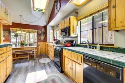 a kitchen with wooden cabinets and a sink and a stove at Central Big Bear Lake Retreat with Private Hot Tub! in Big Bear Lake