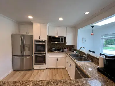 a kitchen with white cabinets and stainless steel appliances at Modern 3 King Beds, Beautiful Large Backyard, WFH, Long Stays, Waterfall, WI-FI, FWY, 25 mins to Beach in Thousand Oaks
