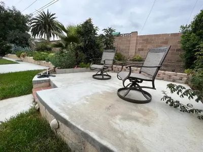 two empty chairs sitting on a concrete patio at Modern 3 King Beds, Beautiful Large Backyard, WFH, Long Stays, Waterfall, WI-FI, FWY, 25 mins to Beach in Thousand Oaks