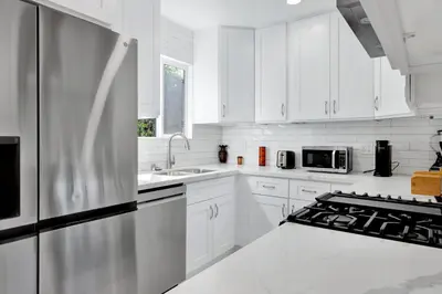 a kitchen with white cabinets and a stainless steel refrigerator at Modern Peaceful Private Oasis Near The Beach in Los Angeles