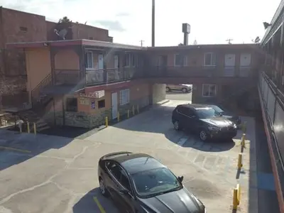 two cars parked in a parking lot under a bridge at TRAVEL INN MOTEL in Los Angeles