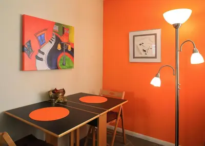 a dining room with an orange wall and a table at Peninsula Hideaway Apartment • Alamitos Bay in Long Beach