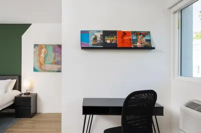 a bedroom with a desk and a bed and paintings at Fenix Hotel Hollywood in Los Angeles
