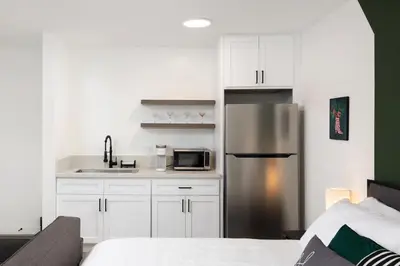 a kitchen with white cabinets and a stainless steel refrigerator at Fenix Hotel Hollywood in Los Angeles