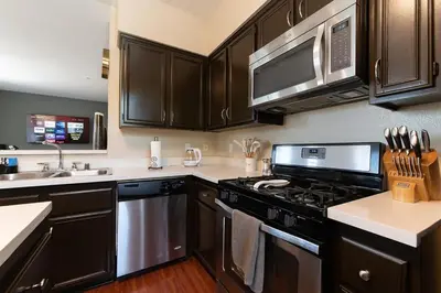 a kitchen with black cabinets and a stove top oven at Saints 2BDRM King Suite Deluxe Living Cali in Santa Clarita