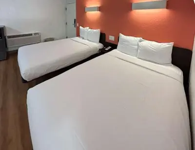 two beds in a hotel room with white sheets at Studio 6 Suites - Riverside, CA South in Riverside