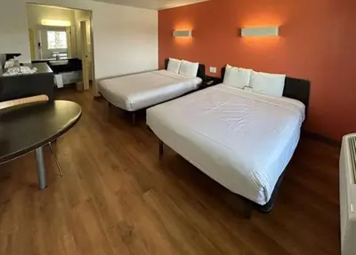 a hotel room with two beds and a table at Studio 6 Suites - Riverside, CA South in Riverside