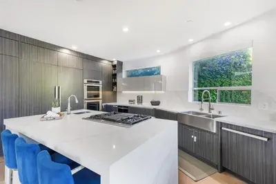 a kitchen with a large white counter and blue chairs at Lindenhurst in Los Angeles
