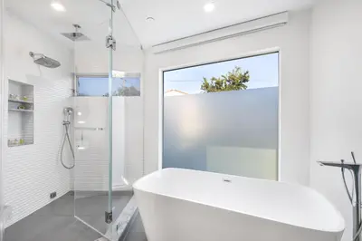 a white bathroom with a tub and a glass shower at Lindenhurst in Los Angeles