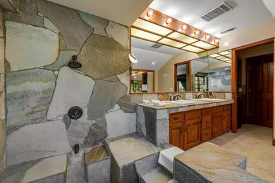 a stone bathroom with a sink and a large mirror at Mountain Memories on Tavern Bay in Lake Arrowhead
