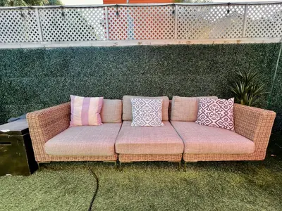 a wicker couch with pillows sitting on the grass at Chic Venice Beach Bungalow Steps from the Canals & Beach in Los Angeles