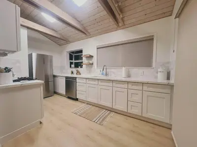 a large kitchen with white cabinets and a large mirror at Summer Lillie #3 in Summerland
