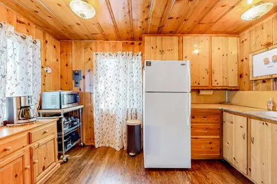 a white refrigerator in a kitchen with wooden cabinets at El Sueńo in Crestline