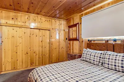 a bedroom with a bed in a wooden wall at El Sueńo in Crestline