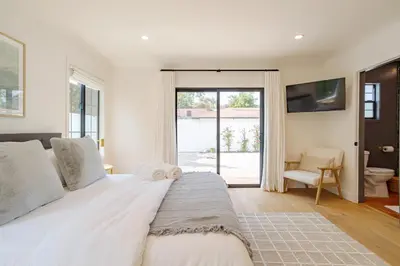 a bedroom with a large white bed and a sliding glass door at Designer 2 bed near Universal sleeps 8 hot tub in Los Angeles
