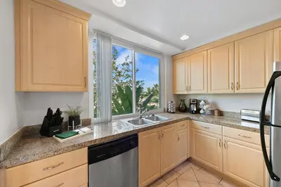 a kitchen with wooden cabinets and a sink and a window at Beverly Hills Glamour Oasis 2 BR Apt with Parking 304 in Los Angeles