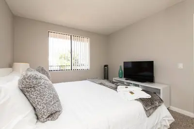 a bedroom with a white bed and a flat screen tv at Skyline Palms 1-Bedroom with Roof-Top Pool in Los Angeles