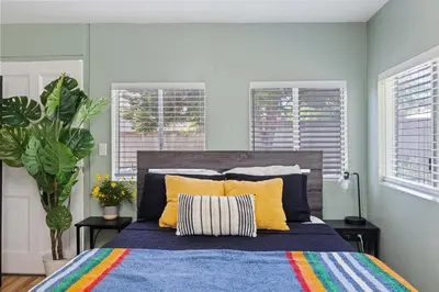 a bedroom with a blue bed with yellow pillows at 5 Mins Walk To Oldtown Monrovia Cozy 4 Br Home in Monrovia