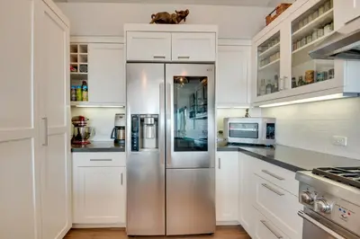 a stainless steel refrigerator in a kitchen with white cabinets at Malibu Retreat with Balcony and Mountain Views in Malibu