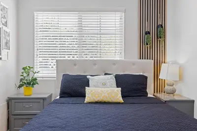 a bedroom with a bed with a blue blanket and a window at Central Location Family Size Home in Temple City