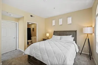 a bedroom with a large white bed and a lamp at Luxury 2BR/2BA! 5 MIN to Disney! in Anaheim