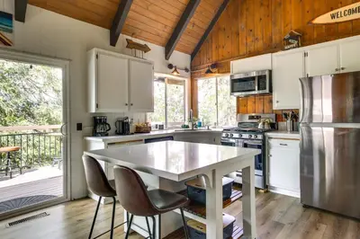 a kitchen with white cabinets and a table and chairs at Cozy and Chic Lake Arrowhead Cabin with Deck! in Lake Arrowhead
