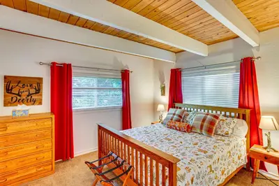 a bedroom with a bed and red drapes at 1 Mi to Lake Arrowhead Village! Cabin with Game Room in Lake Arrowhead
