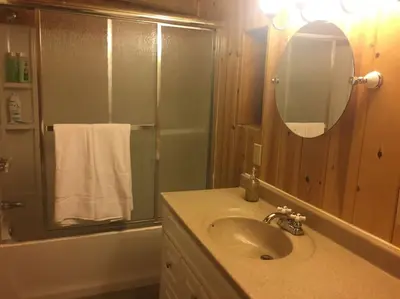 a bathroom with a sink and a mirror and a tub at Tillie Creek Retreat: a Creekside Oasis in Wofford Heights