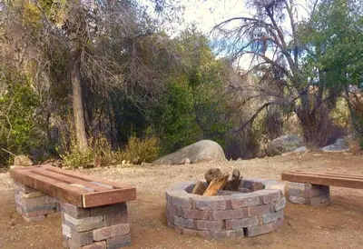 a fire pit with a bench and a picnic table at Shirley Creek Retreat: a Mountain Oasis in Wofford Heights