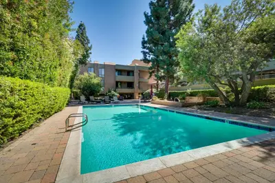 a swimming pool with trees and a building at Granada Hills Condo with Community Pool and Workspace in Los Angeles
