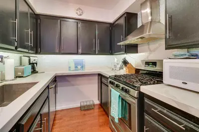 a kitchen with black cabinets and a stove top oven at Granada Hills Condo with Community Pool and Workspace in Los Angeles