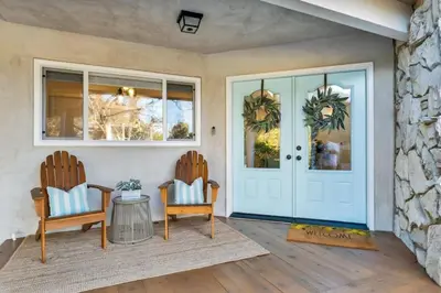 a front door of a home with two chairs and a table at Modern Family Farmhouse with Pool, Jacuzzi, Putting Green, Treehouse, Bocce and more in Thousand Oaks