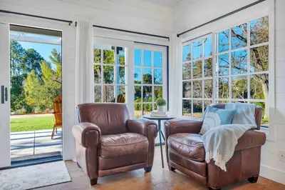 two chairs and a table in a room with windows at Modern Family Farmhouse with Pool, Jacuzzi, Putting Green, Treehouse, Bocce and more in Thousand Oaks