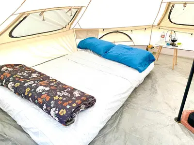 a bed in a tent with blue pillows on it at Beysicair Tents & Campground in California City