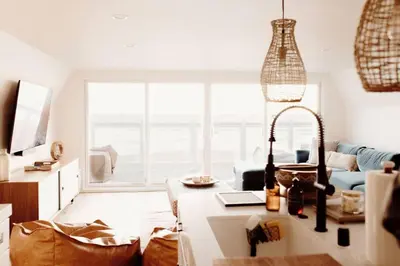 a living room with a large window and a table at Oceanfront Penthouse On Sand - Epic Views/Sunsets! in Huntington Beach