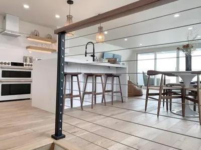 a kitchen with a counter and a table with stools at Oceanfront Penthouse On Sand - Epic Views/Sunsets! in Huntington Beach