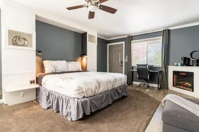a bedroom with a bed with a ceiling fan and a desk at Big Bear Spa Suites in Big Bear Lake