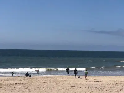 a group of people walking on the beach at The Shores Inn in Ventura