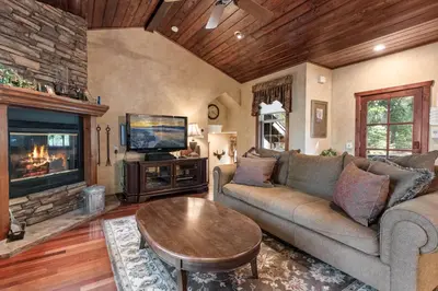 a living room with a couch and a table and a tv at Big Bear Villa - Walk to Lake ad Village! Hot Tub, Jet Tub and so much more! in Big Bear Lake