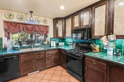 a kitchen with wooden cabinets and black appliances at Big Bear Villa - Walk to Lake ad Village! Hot Tub, Jet Tub and so much more! in Big Bear Lake