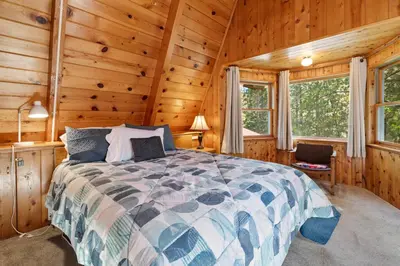 a bedroom with a bed in a log cabin at Kapers - Located in a beautiful quiet area of Big Bear Lake, walking distance to Snow Summit! in Big Bear Lake