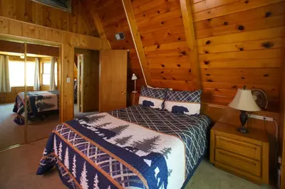 a bedroom with a bed in a log cabin at Kapers - Located in a beautiful quiet area of Big Bear Lake, walking distance to Snow Summit! in Big Bear Lake