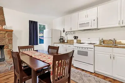 a kitchen with white cabinets and a table with chairs at The Weekender- Adorable Modern Chic Cottage in Big Bear City