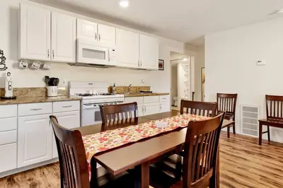 a kitchen with a table and chairs and white cabinets at The Weekender- Adorable Modern Chic Cottage in Big Bear City