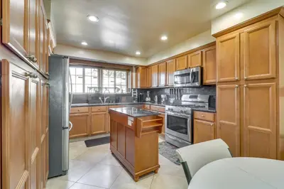 a kitchen with wooden cabinets and stainless steel appliances at North Hills Home with Outdoor Entertaining Space in North Hills
