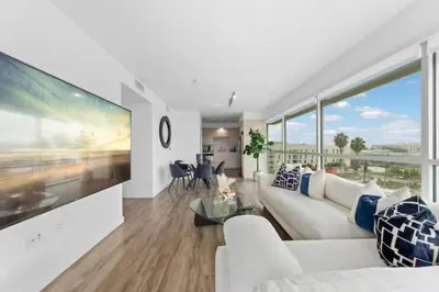 a living room with a white couch and a large tv at Amber Drift - Santa Monica 2BR Penthouse Ocean views in Los Angeles