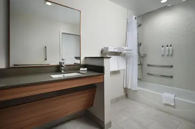 a bathroom with a sink and a tub and a mirror at Fairfield by Marriott Inn & Suites Barstow in Barstow