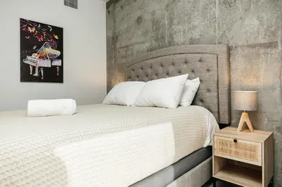 a bedroom with a large bed with a concrete wall at Oasis in heart of Hollywood in Los Angeles