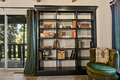 a book shelf with books and a chair in a room at Romantic & Family Friendly Chalet In The Woods in Lake Arrowhead